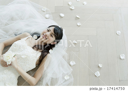 ウェディングドレス姿で寝そべる若い女性の写真素材