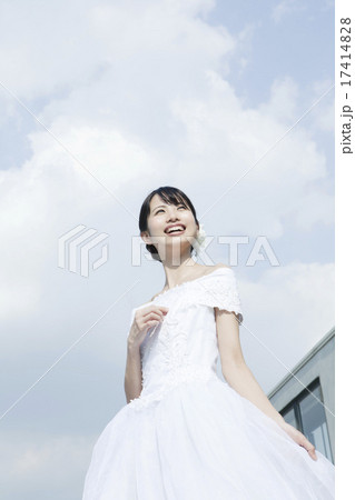 青空とウェディングドレス姿の若い女性 17414828