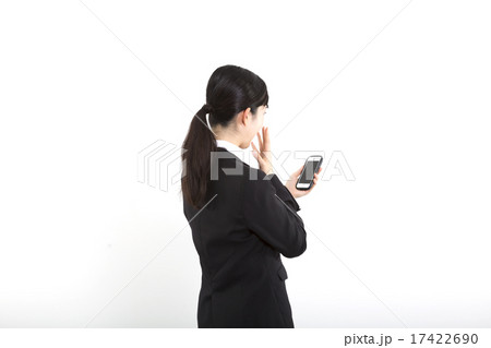 ビジネス 女性 白バック スマホ 驚く 後ろ姿の写真素材