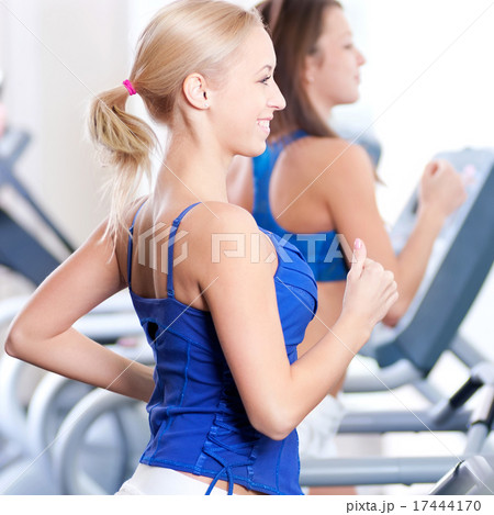 Two young women run on machine in the gym 17444170