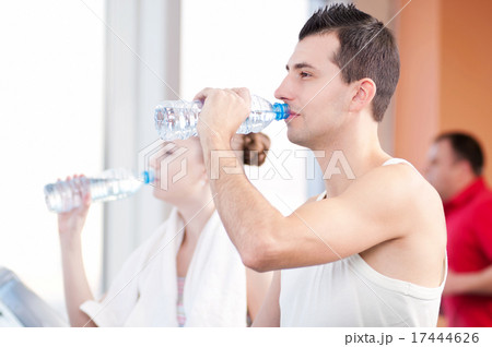 Man and woman drinking water after sports in gym Man and woman drinking water after sports in gym 17444626