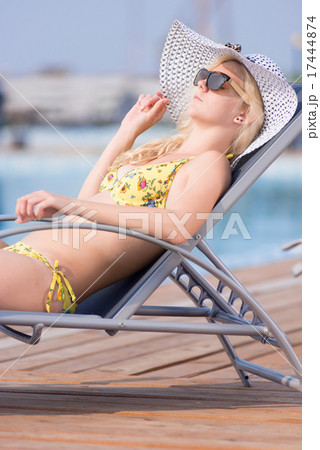 Young woman in swimsuit laying on chaise-longue poolside 17444874