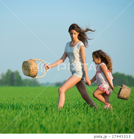 Young happy girls running witch baskets at green wheat field 17445313