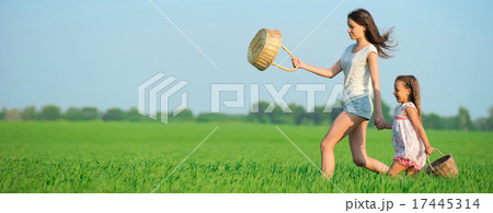 Young happy girls running witch baskets at green wheat field 17445314