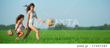 Young happy girls running witch baskets at green wheat field 17445384