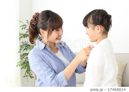 洋服のボタンを留めるお母さん 17468024
