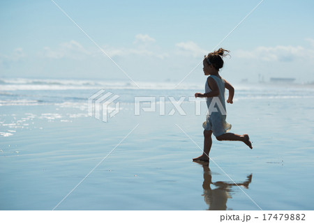 海を走る女の子のシルエットの写真素材