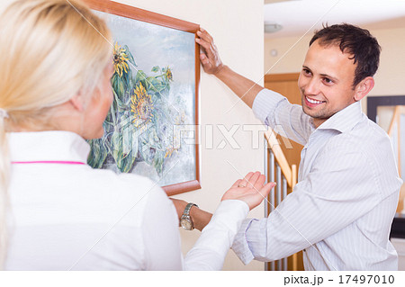 Couple hanging art picture in frame 17497010