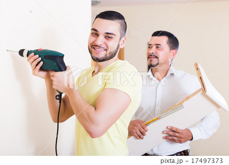 Son and father drilling wall Son and father drilling wall 17497373