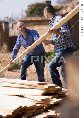 workmen arranging building timber at farm 17497438
