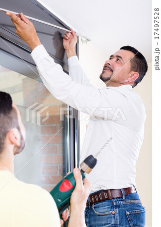Men hang blinds 17497528