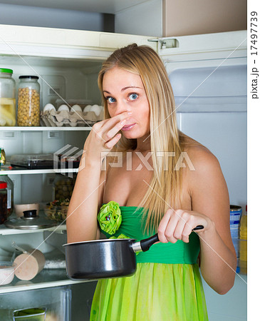 Woman holding foul food near fridge Woman holding foul food near fridge 17497739
