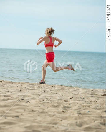 Young lady running at the sunny summer sand beach. Workout. Jog 17499624