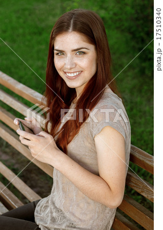 Portrait of young woman in park texting on a phone Portrait of young woman in park texting on a phone 17510340