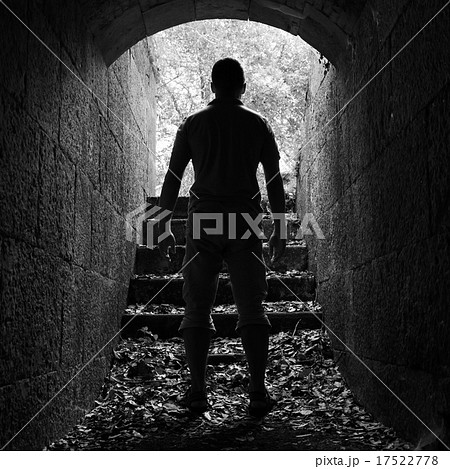 Young man stands in dark stone tunnel 17522778
