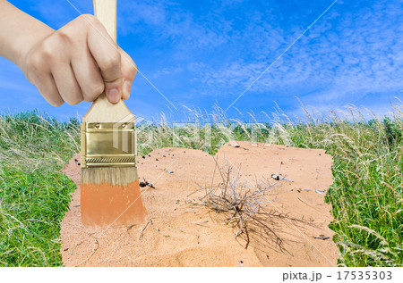 hand with paintbrush paints sand in green meadow hand with paintbrush paints sand in green meadow 17535303