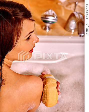 Woman using bath sponge in bathtub. 17545774
