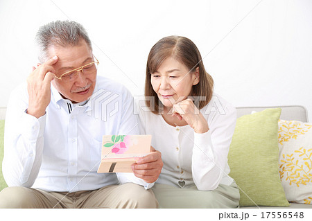 通帳を見て悩むシニア夫婦 17556548