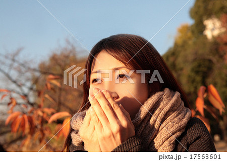 寒そうに手を暖める若い可愛い女性の写真素材
