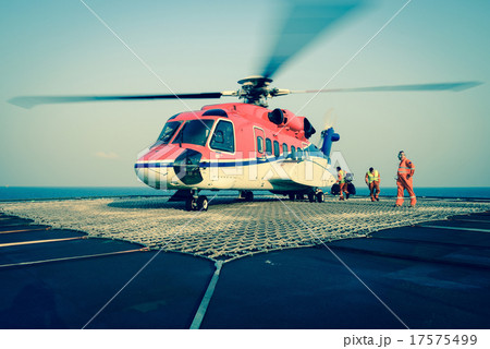The officer take care passenger to embark helicopter at oil rig 17575499