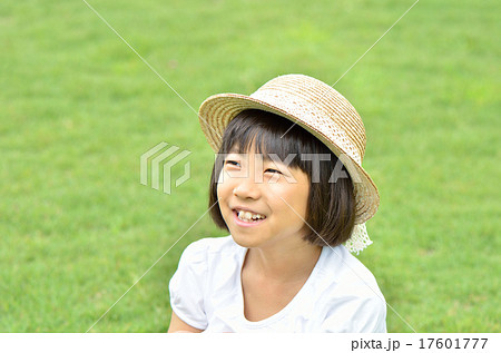 芝生広場に座る女の子 麦わら帽子 の写真素材