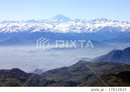 遠く南米最高峰のアコンカグアを望む南米チリのアンデス山脈と朝霧に煙る谷間の高原の町の写真素材