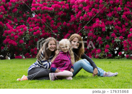 mother with daughters sitting on a grass 17635868