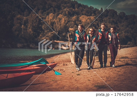 Group of people wearing life jackets near kayaks on a beach 17642958