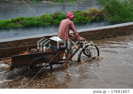 雨季のインド 首都デリー 洪水の中、自転車を漕ぐインド人の写真素材