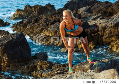 Athlete woman standing after sport exercising on the rocks by th Athlete woman standing after sport exercising on the rocks by th 17712008