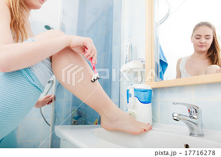 Woman shaving legs with razor in bathroom Woman shaving legs with razor in bathroom 17716278
