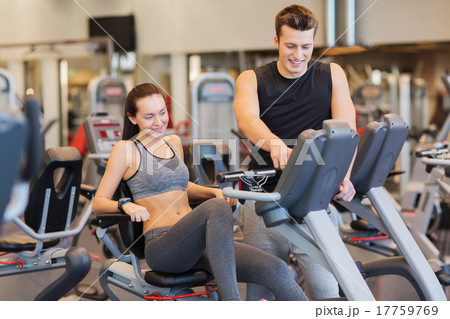 happy woman with trainer on exercise bike in gym happy woman with trainer on exercise bike in gym 17759769