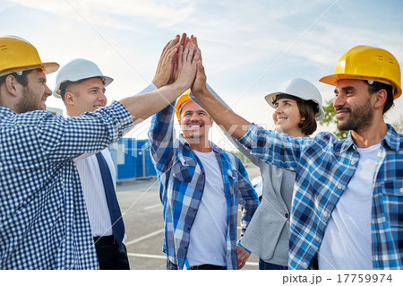 close up of builders in hardhats making high five close up of builders in hardhats making high five 17759974