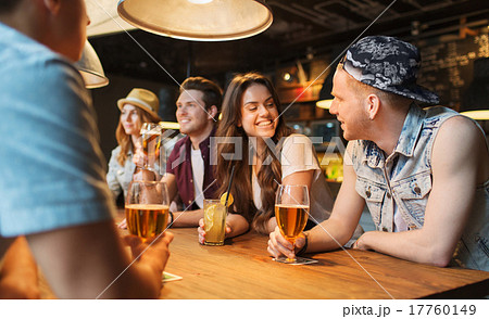 happy friends with drinks talking at bar or pub 17760149