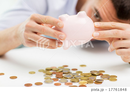 close up of man pouring coins from piggy bank close up of man pouring coins from piggy bank 17761848
