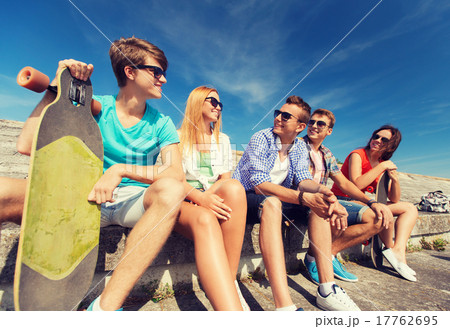 group of smiling friends sitting on city street 17762695