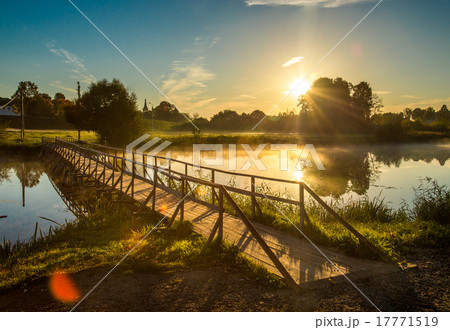 wooden bridge through river in morning sunlight wooden bridge through river in morning sunlight 17771519