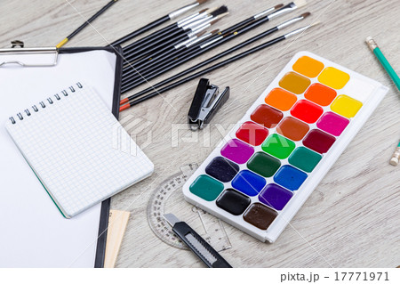 Paper, pencils, brush, green apple on wooden table 17771971
