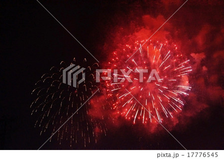 天然デザイン花火の背景素材・夜空ににじむ打ち上げ花火の火と煙りの軌跡・赤系白系大輪と赤煙横位置 17776545