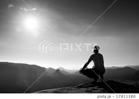 Runner sit  in squatting position on a rock 17811380