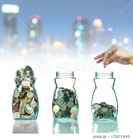 Hand putting mix coins in clear bottle on cityscape photo blurre 17823940