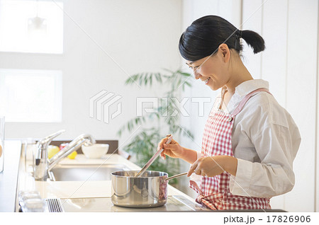 明るいキッチンで料理する女性の写真素材