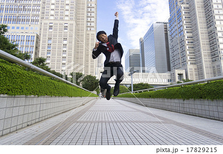 アクションポーズ ジャンプするビジネスマン ブレ 新宿高層ビル街 ガッツポーズの写真素材