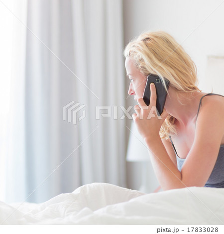Woman talking by phone on bed in morning. Woman talking by phone on bed in morning. 17833028