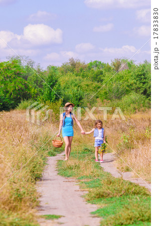 Girls sister in a field with a basket and flowers 17833830