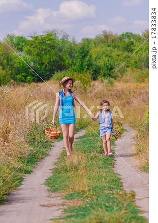 Girls sister in a field with a basket and flowers Girls sister in a field with a basket and flowers 17833834