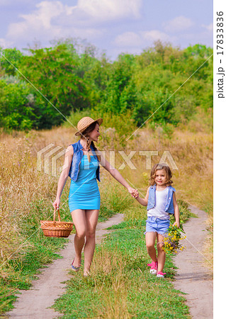 Girls sister in a field with a basket and flowers 17833836