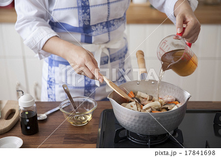 鶏肉と野菜を炒めた鍋に出汁を入れる女性 鶏肉と野菜を炒めた鍋に出汁を入れる女性 17841698