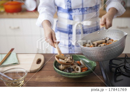 筑前煮を鍋から皿へ盛り付ける女性 17841769