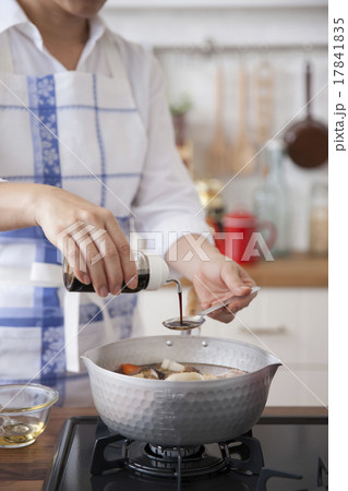 煮物の鍋に調味料を入れる女性 17841835